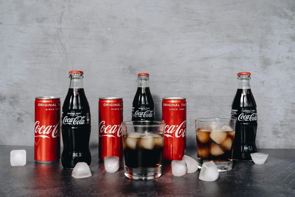 Chilled Coca Cola bottles and cans surrounded by ice cubes, offering a refreshing beverage choice.
